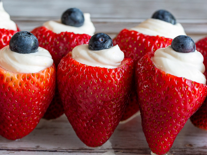 Red, white and blue strawberries are lined up in a row in the refrigerator.