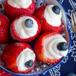 Bowl of strawberries stuffed with lemon cream cheese filling and topped with a blueberry.