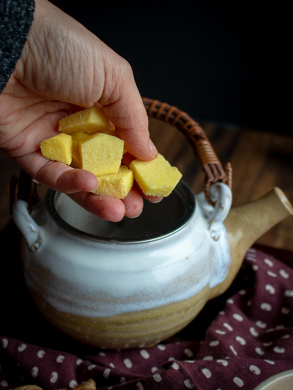 Fresh ginger getting added to the tea pot. 