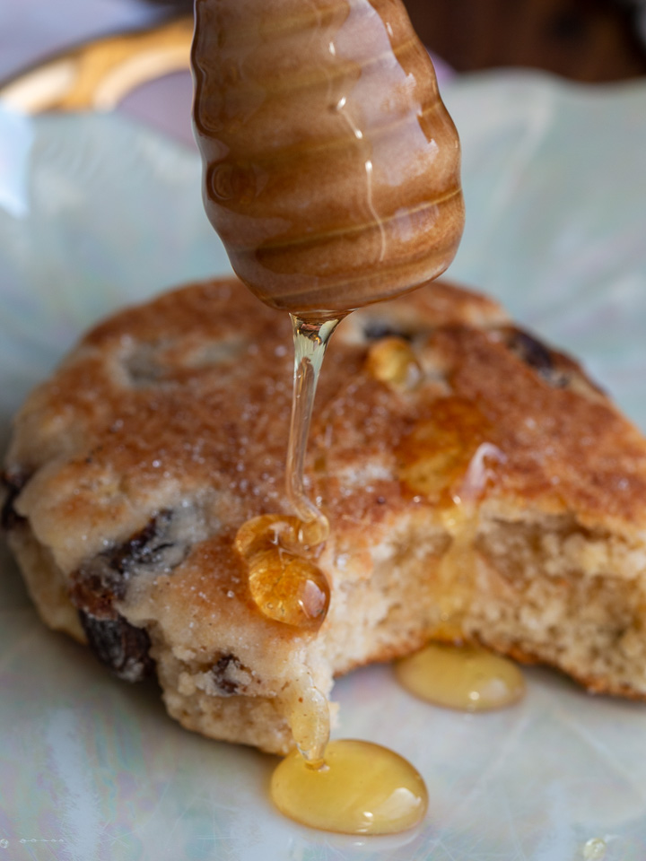 Honey getting drizzled over a freshly cooked Welsh tea cake.