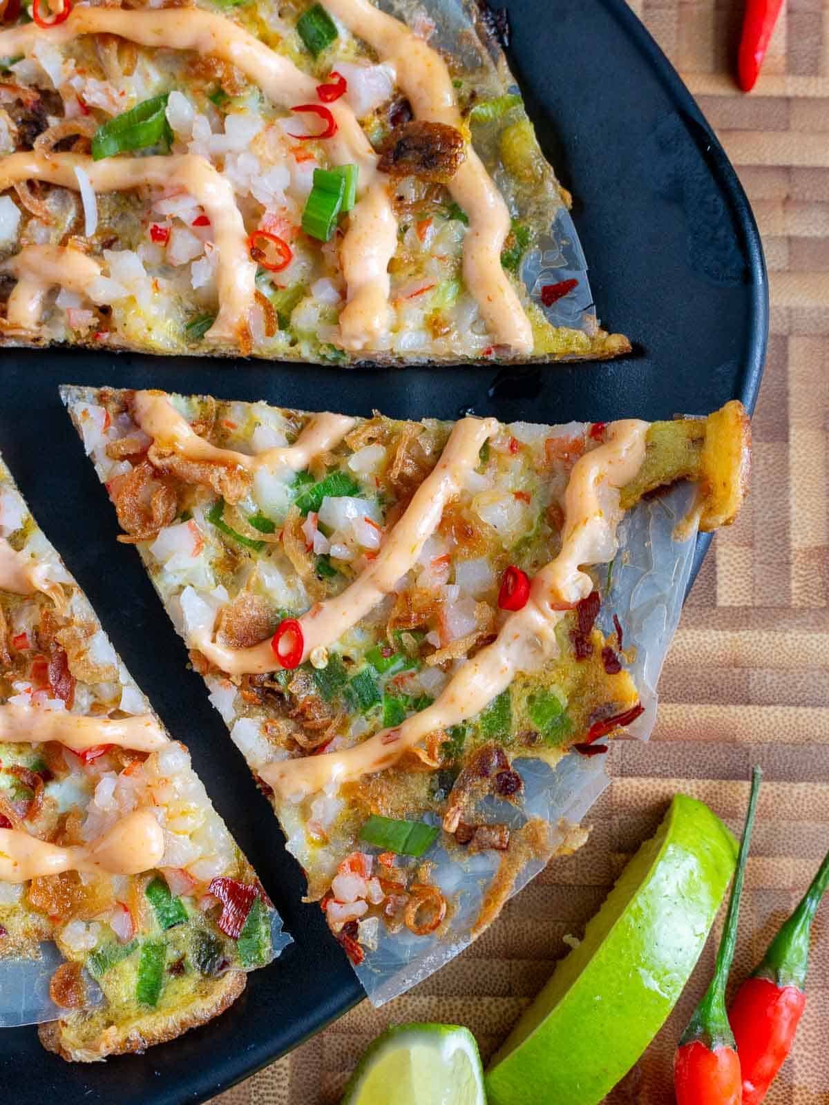 Rice paper pizza cut into wedges and garnished with limes.