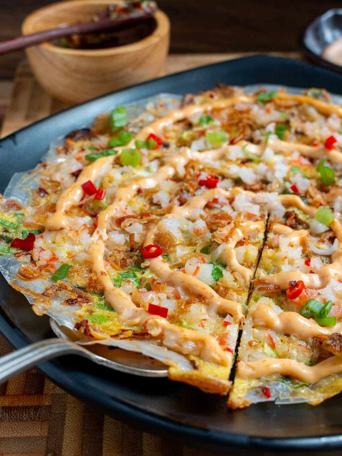 Taking a slice of Bánh Tráng Nướng topped with crab.