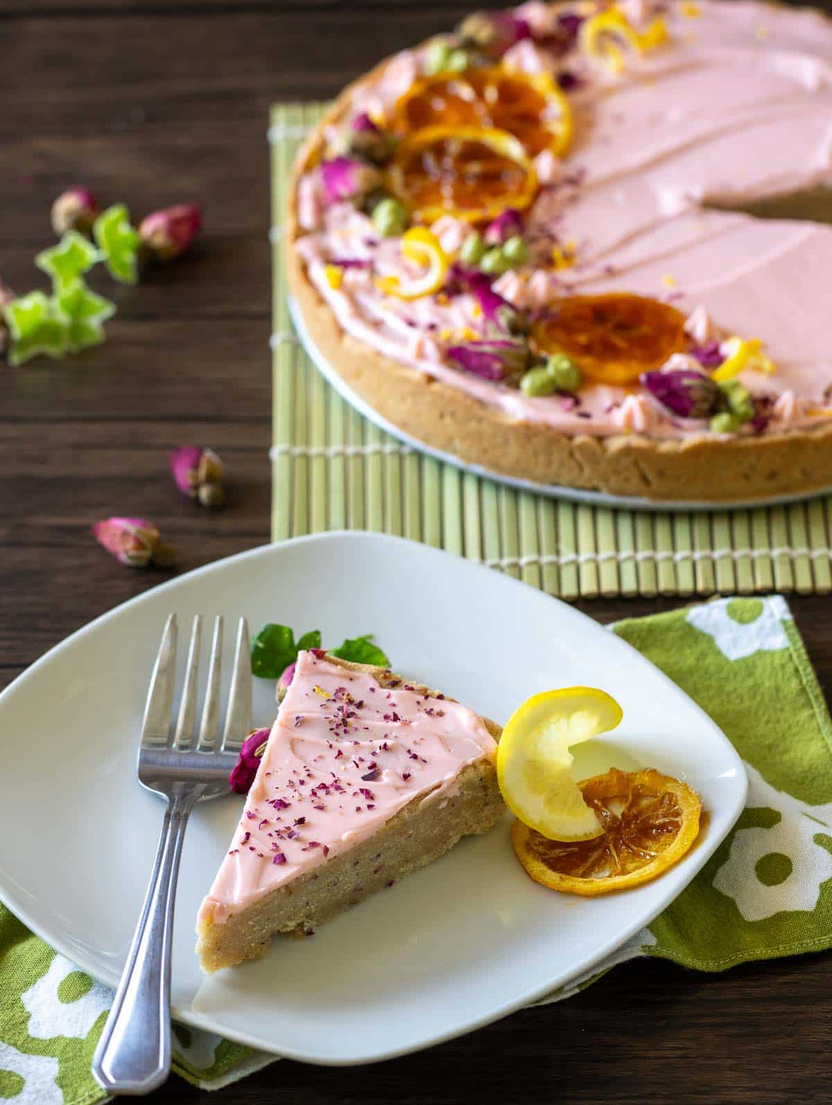 Serving up a slice of rose cookie cake on a white plate with the dessert in the background.