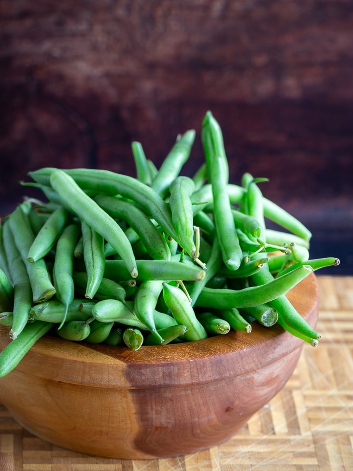 A cherry wooden bowl filled with about one pound of fresh green beans.