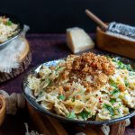 2 plates of Farfalle Aglio e Olio with Breadcrumbs with parmesan and red pepper flakes for extra garnishes.