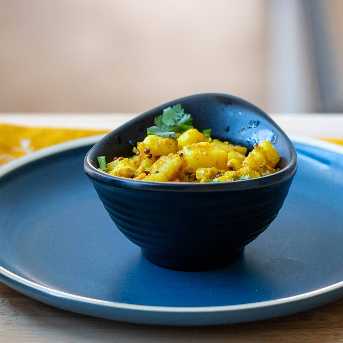 Bowl of aloo masala - spiced Indian potatoes in a black bowl.