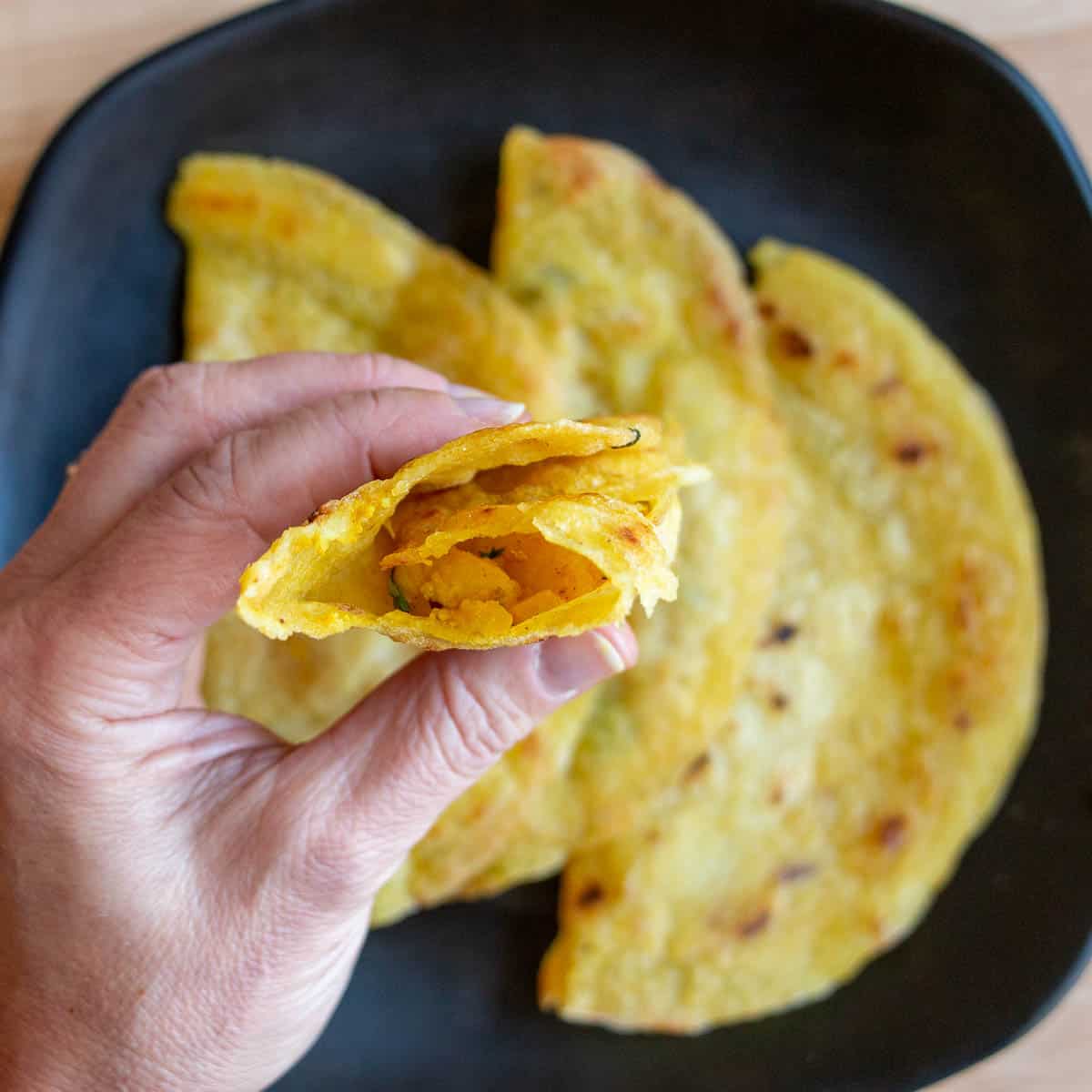 Taking a bite out of a gluten free dosa with aloo masala inside. 