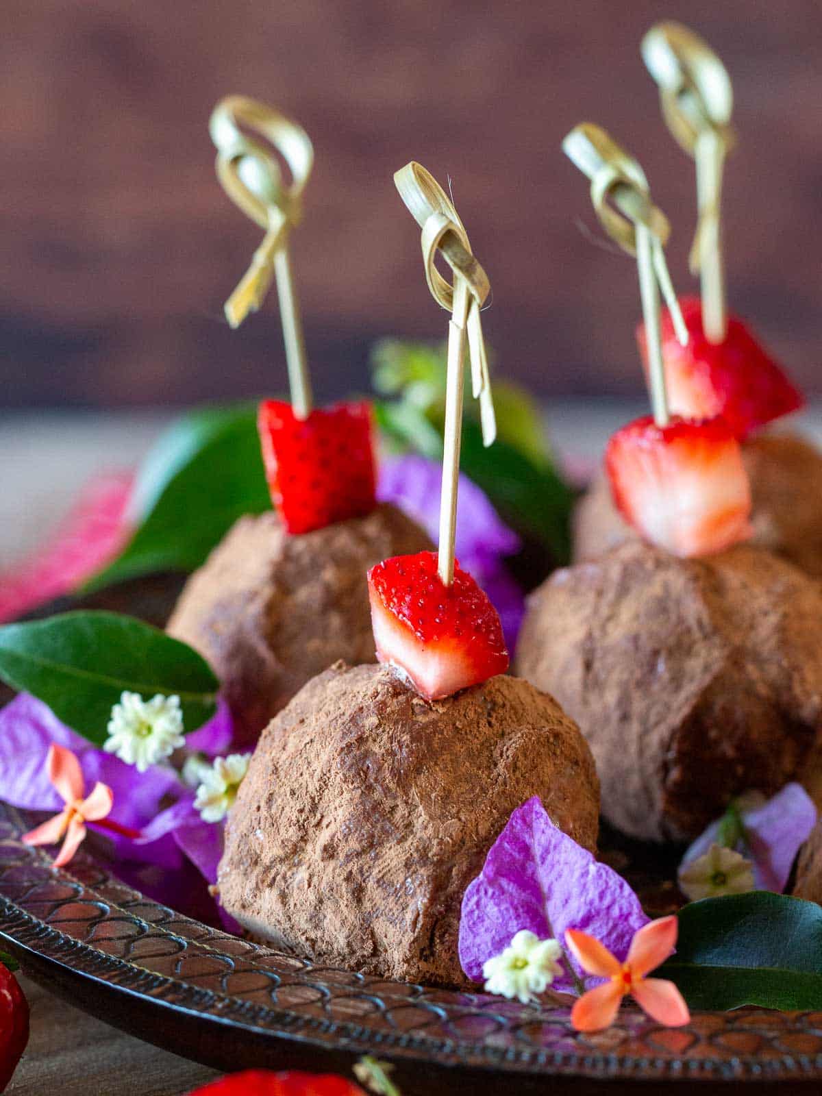 Close up shot of the decorated dessert balls with slices of strawberries and twisted toothpicks.