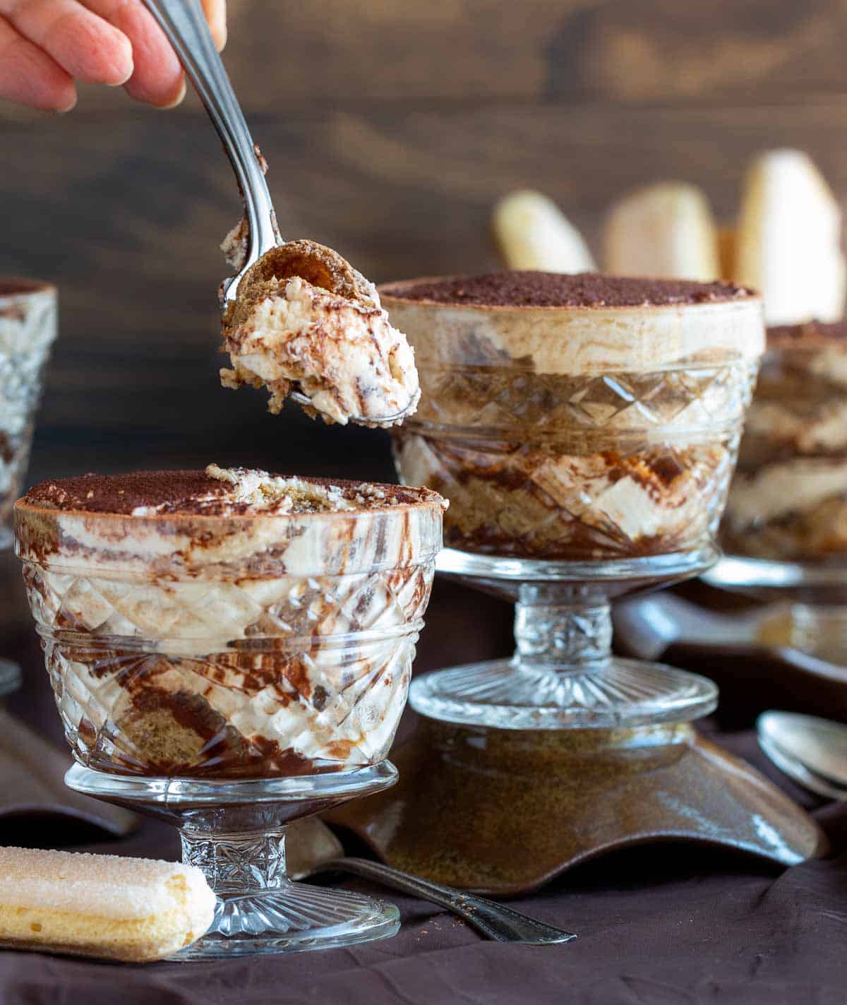 Taking a bite out of an individual tiramisu showing all the delicious cream and sponge cake layers.