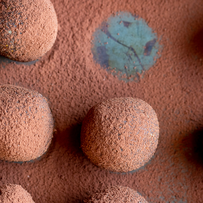 Top down shot of chocolate espresso fig balls with cocoa powder dusted on top with one ball removed. 