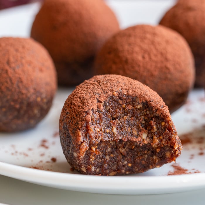 Plate of chocolate Espresso Fig Balls on a white plate with a but out of the one in the front.