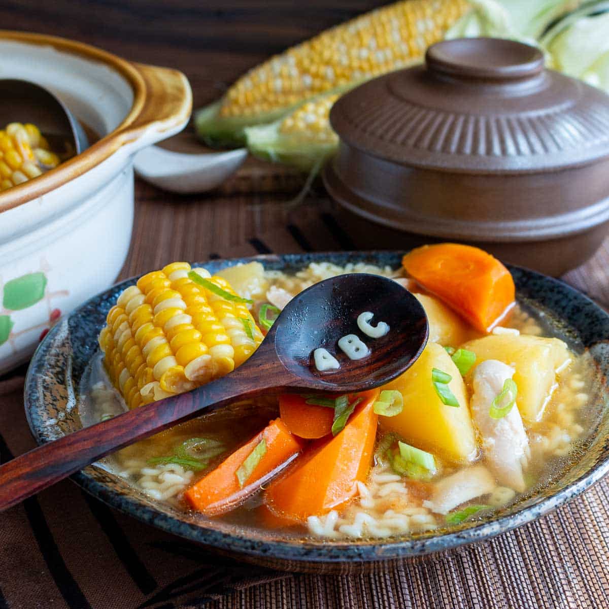 Chinese ABC soup with vegetables an chicken and alphabet pasta forming the letters ABC on a wooden spoon. 