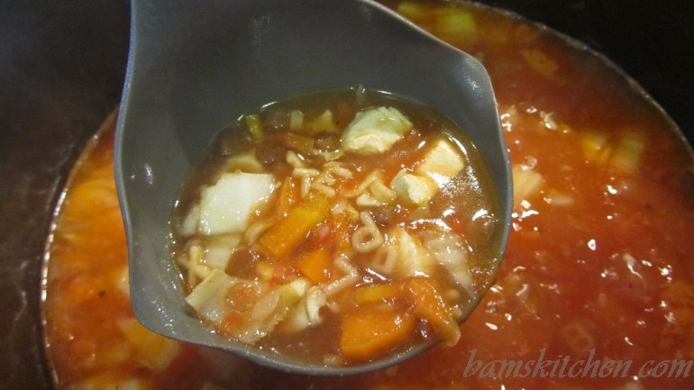 Zippy Veggie ABC Soup scooped into a ladle. 