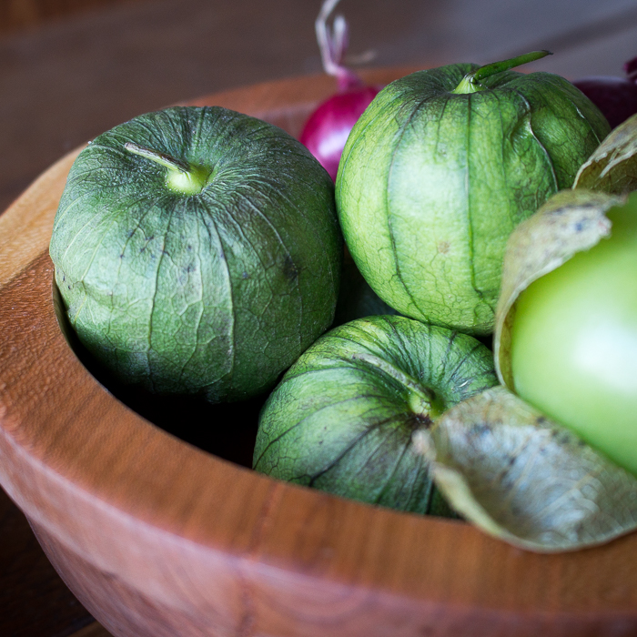 Close up of raw unpeeled tomatillos in a wooden bowl