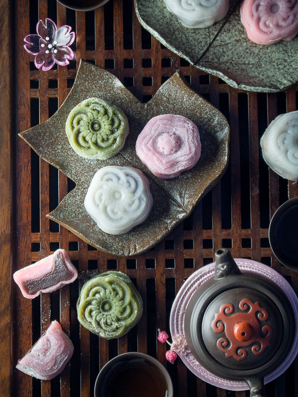 Homemade snowy mooncakes served with tea and colored green and pink. 