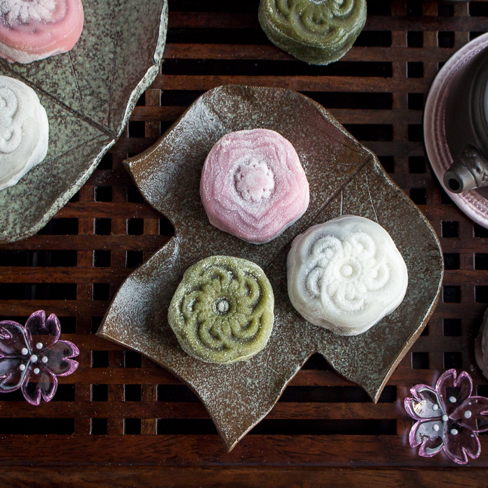 Snow skin mooncake with sweet red bean paste on a leaf plate served with tea.