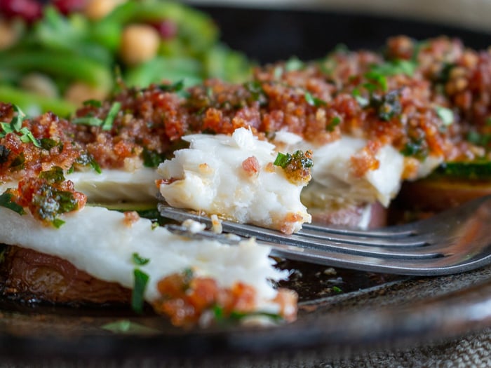 The bite shot of the flaky baked fish.