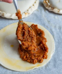 Placing 2 tablespoons of pumpking pie filling over ½ of the cut out pie circle dough.