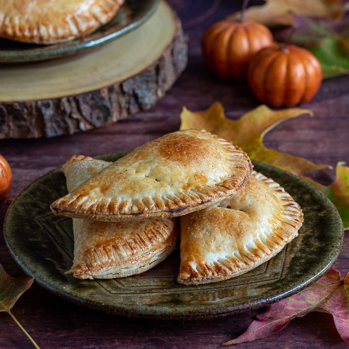 Fall scene with pumpkins, leaves and hand pies on a plate. 