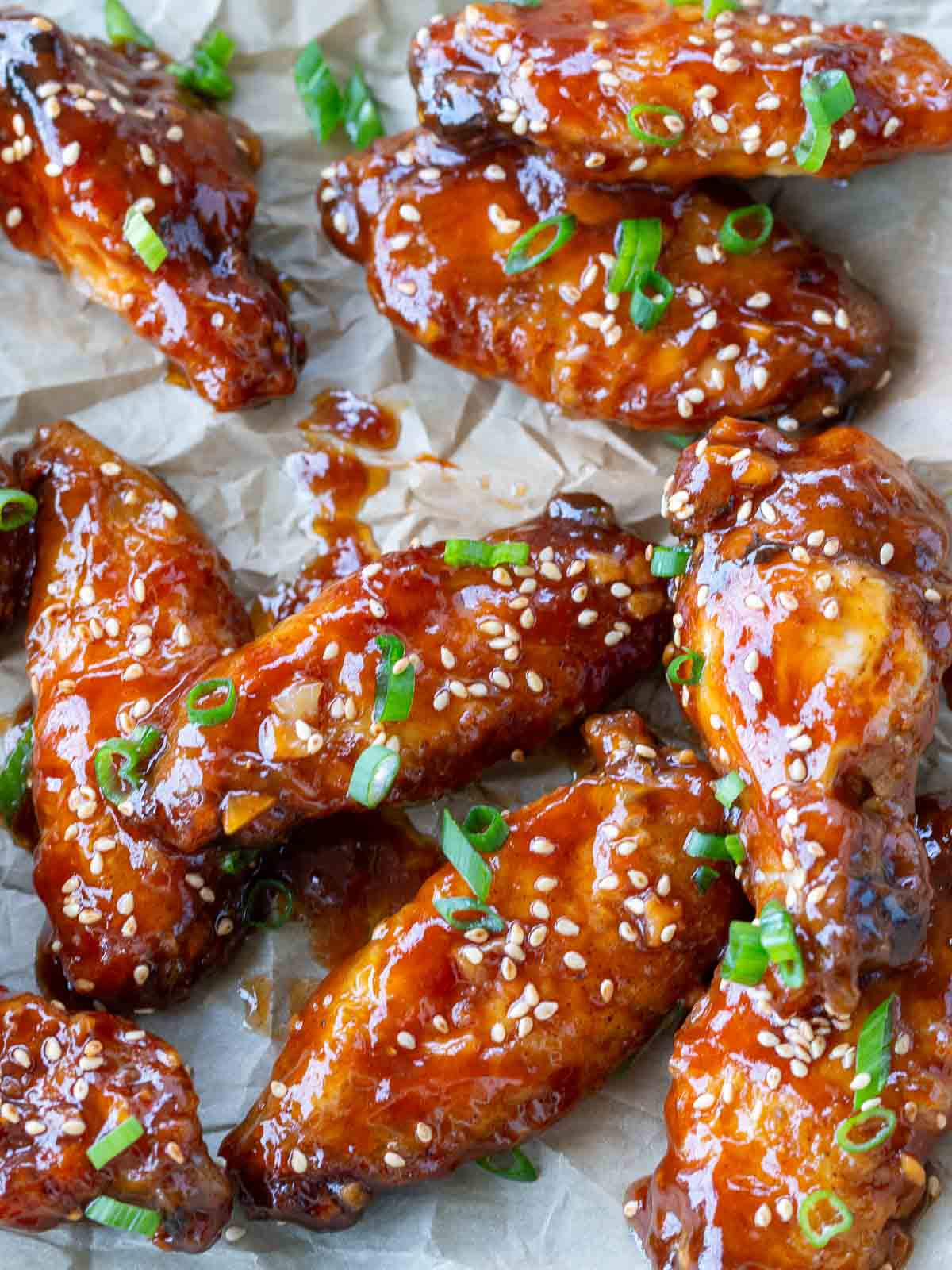 Sticky Asian wings garnished with green onions and sesame seeds.
