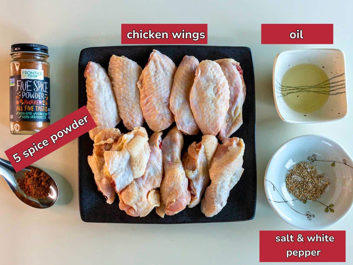 Ingredients to make baked 5 spice chicken wings on a beige table.