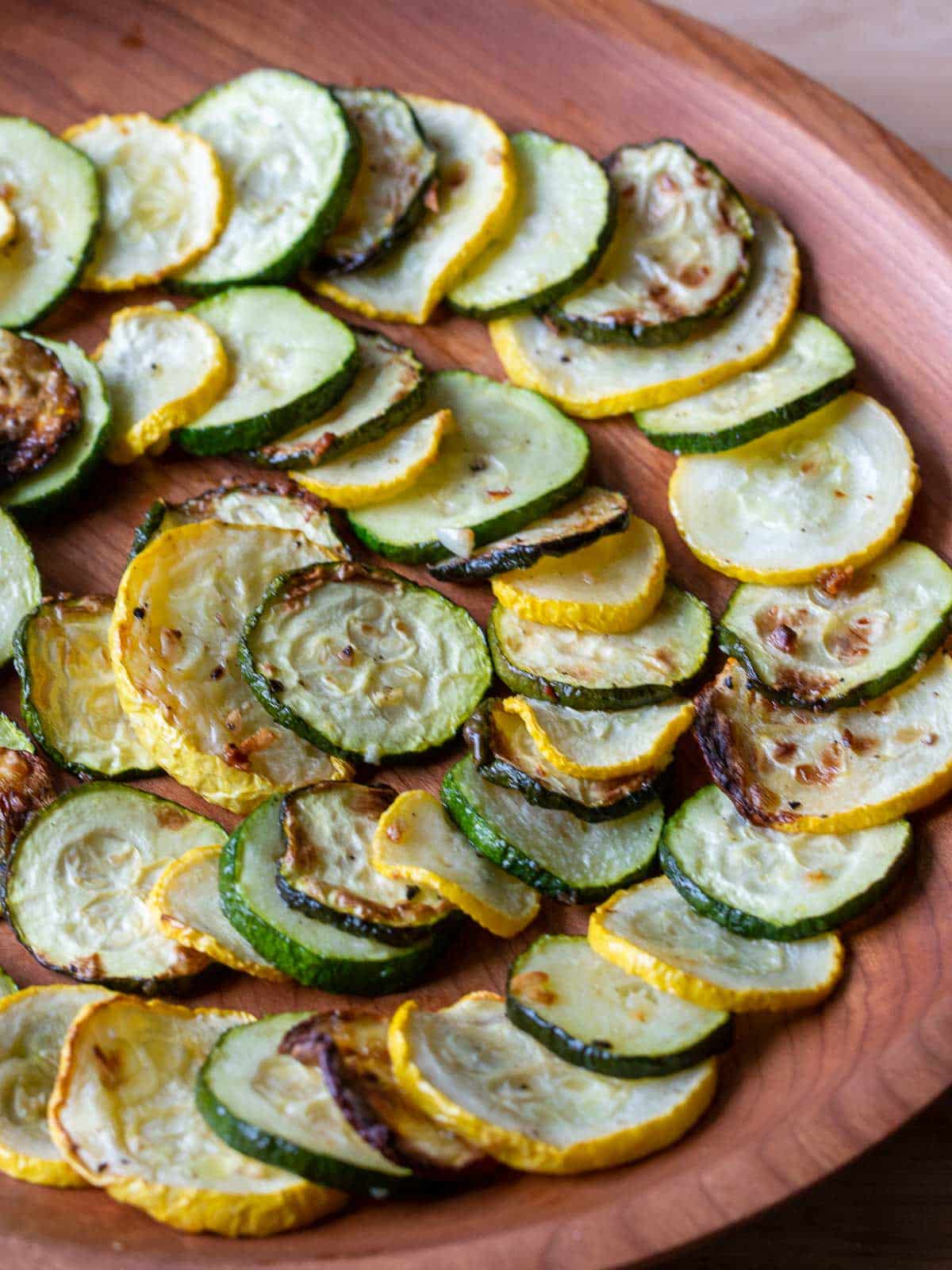 low carb vegetables stacked in a circular design on a wooden plate.