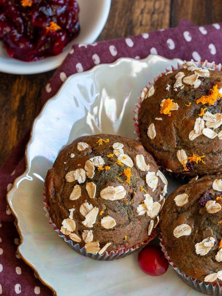 A little bowl of leftover cranberry sauce next to 3 muffins.