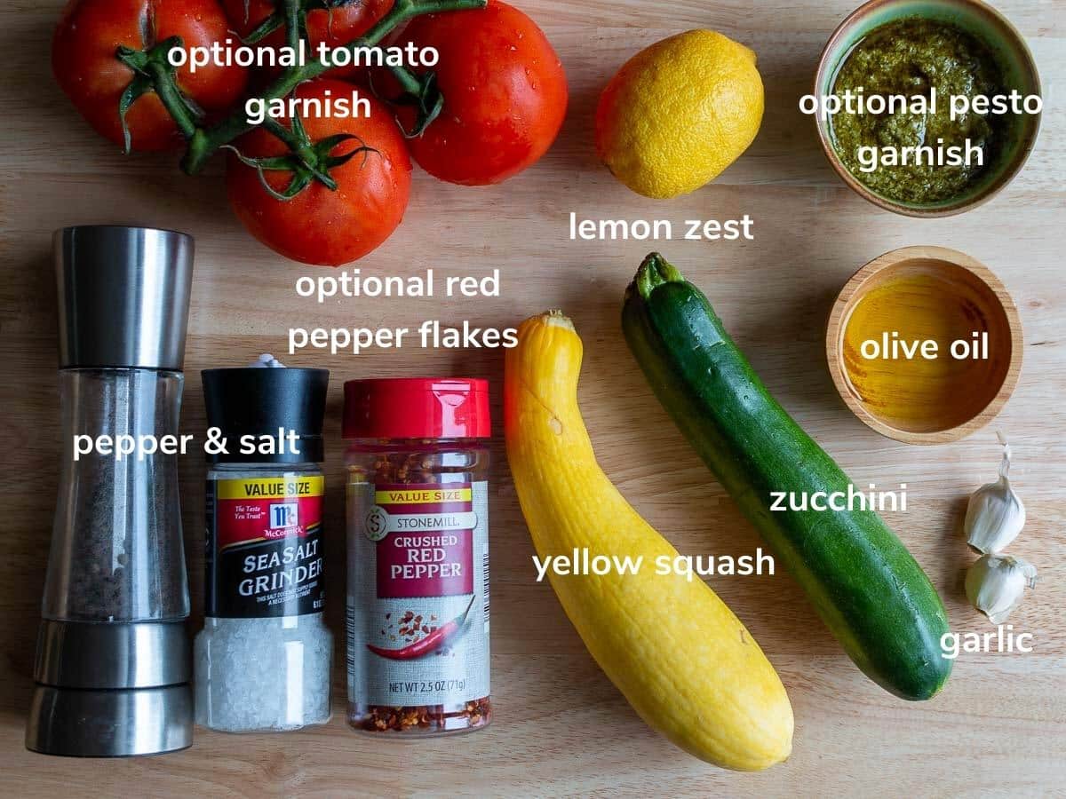 Ingredients to make air fried squash and zucchini on a light wooden cutting board.