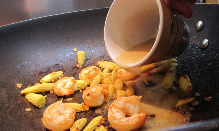 Cornstarch slurry getting added to the vegetables and shrimp in the wok.