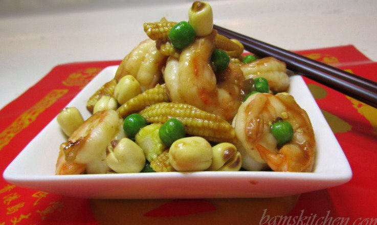 Lucky shrimps and Lotus Seeds on a white plate with chopsticks and a red napkin.