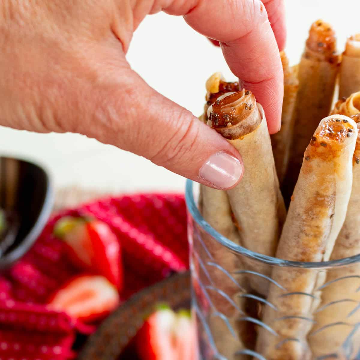 Picking out a crispy strawberry cookie from a tall bowl. 