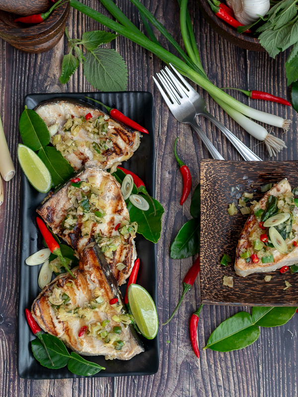 Grilled swordfish ready to serve on a black plate.
