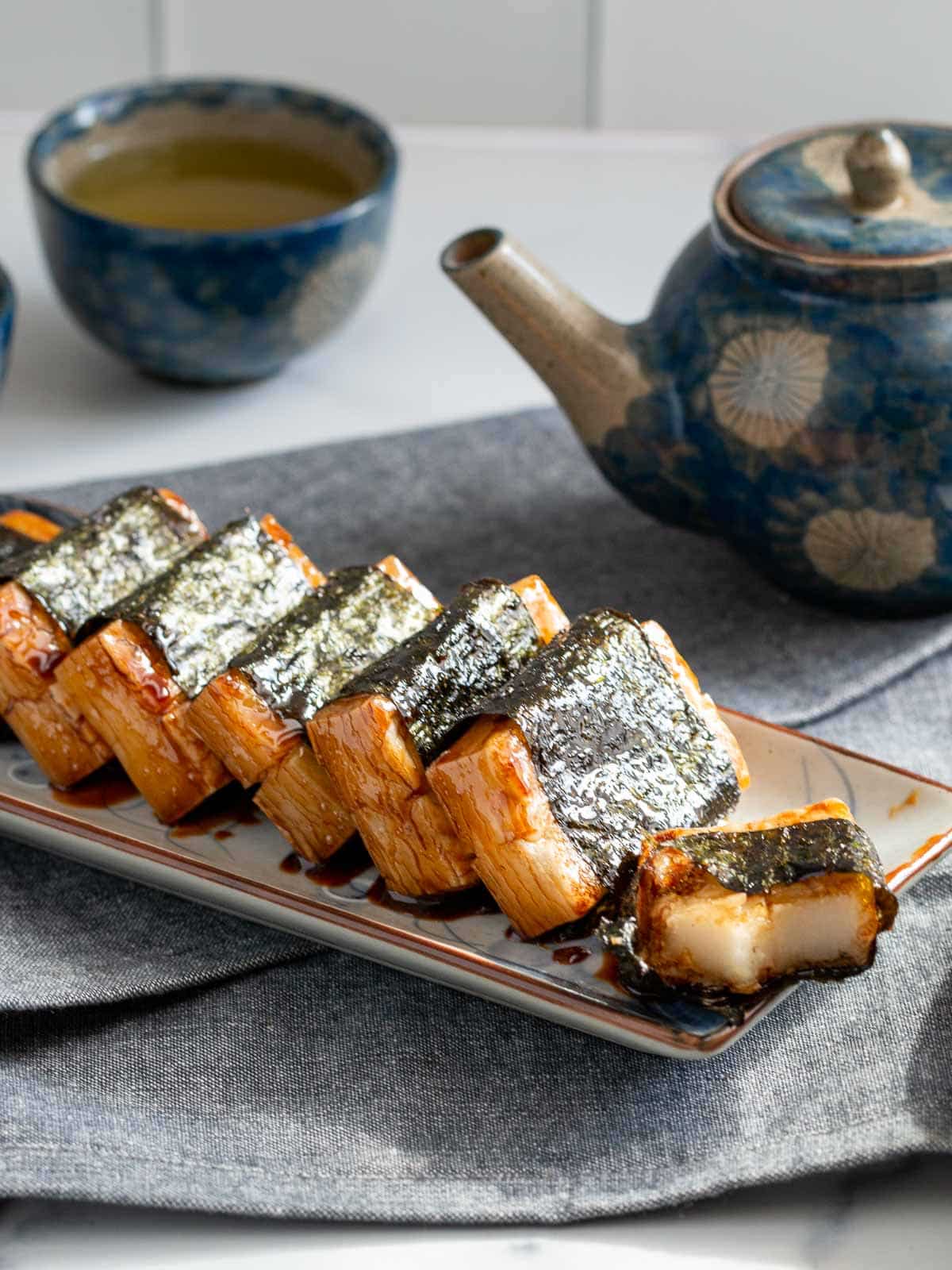 Isobeyaki mochi on a rectangle Japanese tray with a bite out of one.