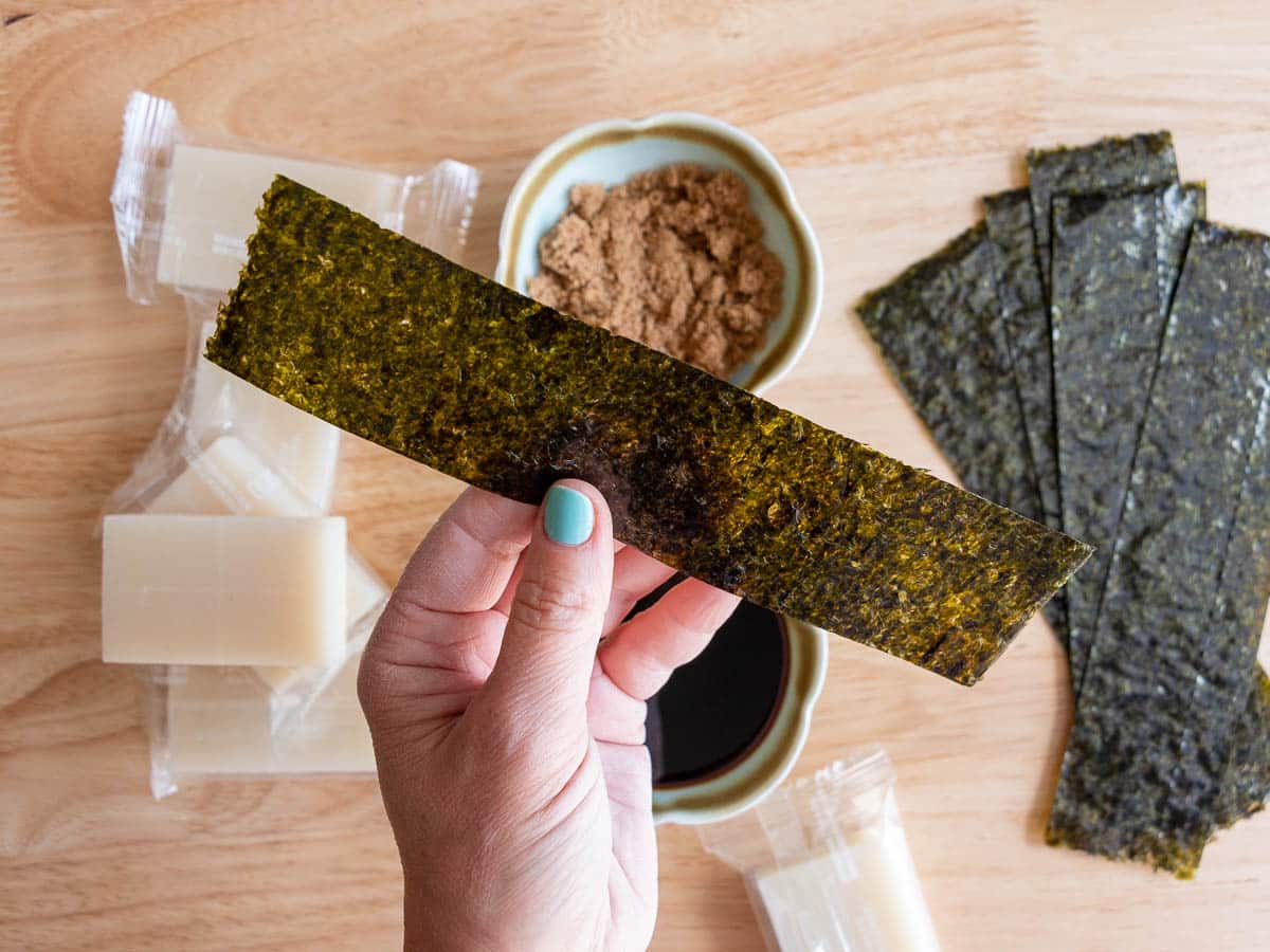 Cut dried roasted seaweed held in a hand.