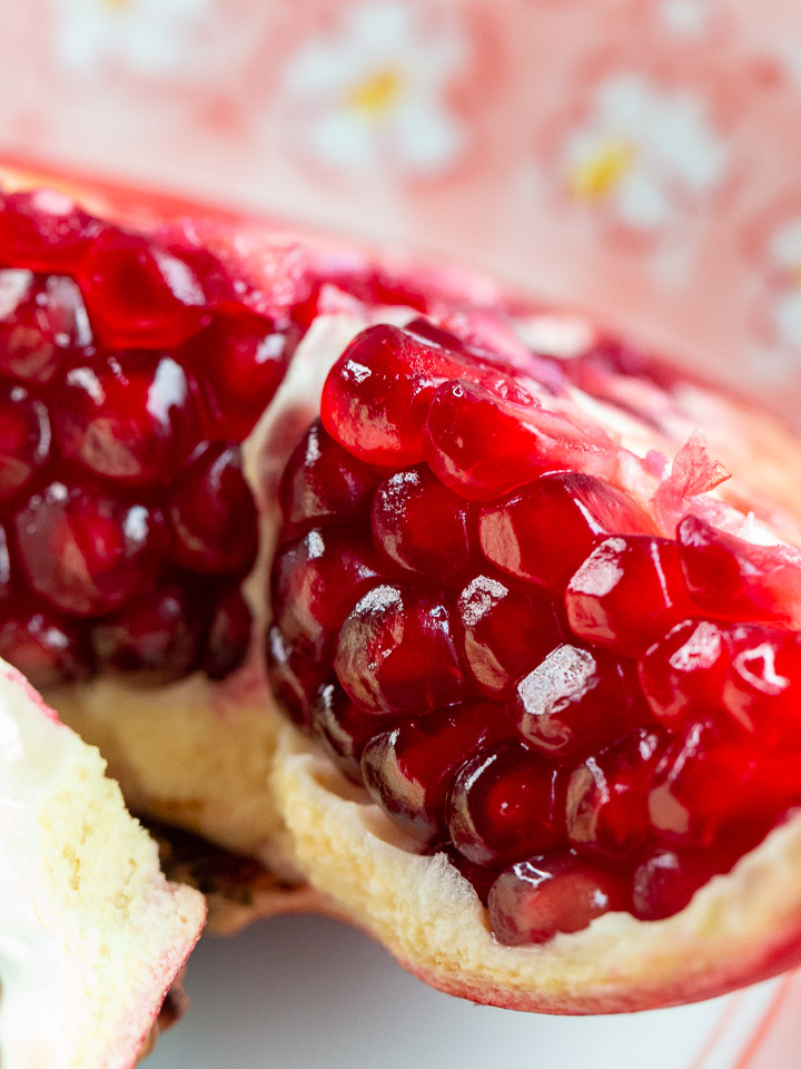 Close up shot of a fresh pomegranate cut into quarters.