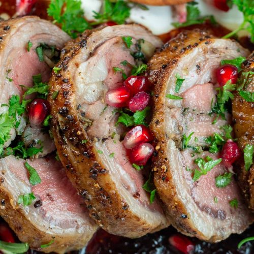 3 slices of lamb loin roast recipe topped with pomegranates and fresh herbs.