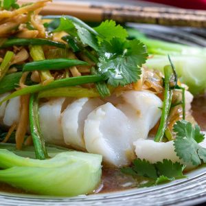 Close ups shot of perfectly steamed cod with ginger and green onions Asian sauce.