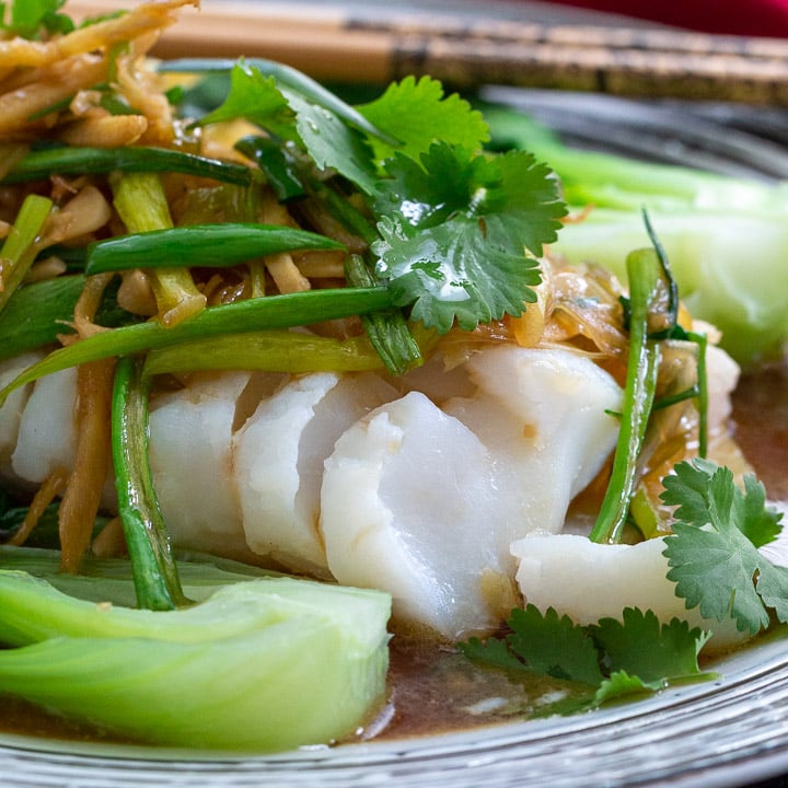 Close up shot of flaky Asian Steamed cod fish topped with Asian Sauce.