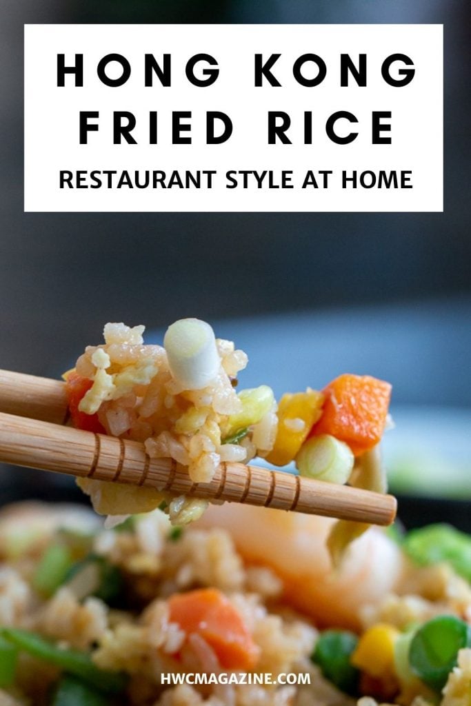 Fried rice getting scooped up with chopsticks.