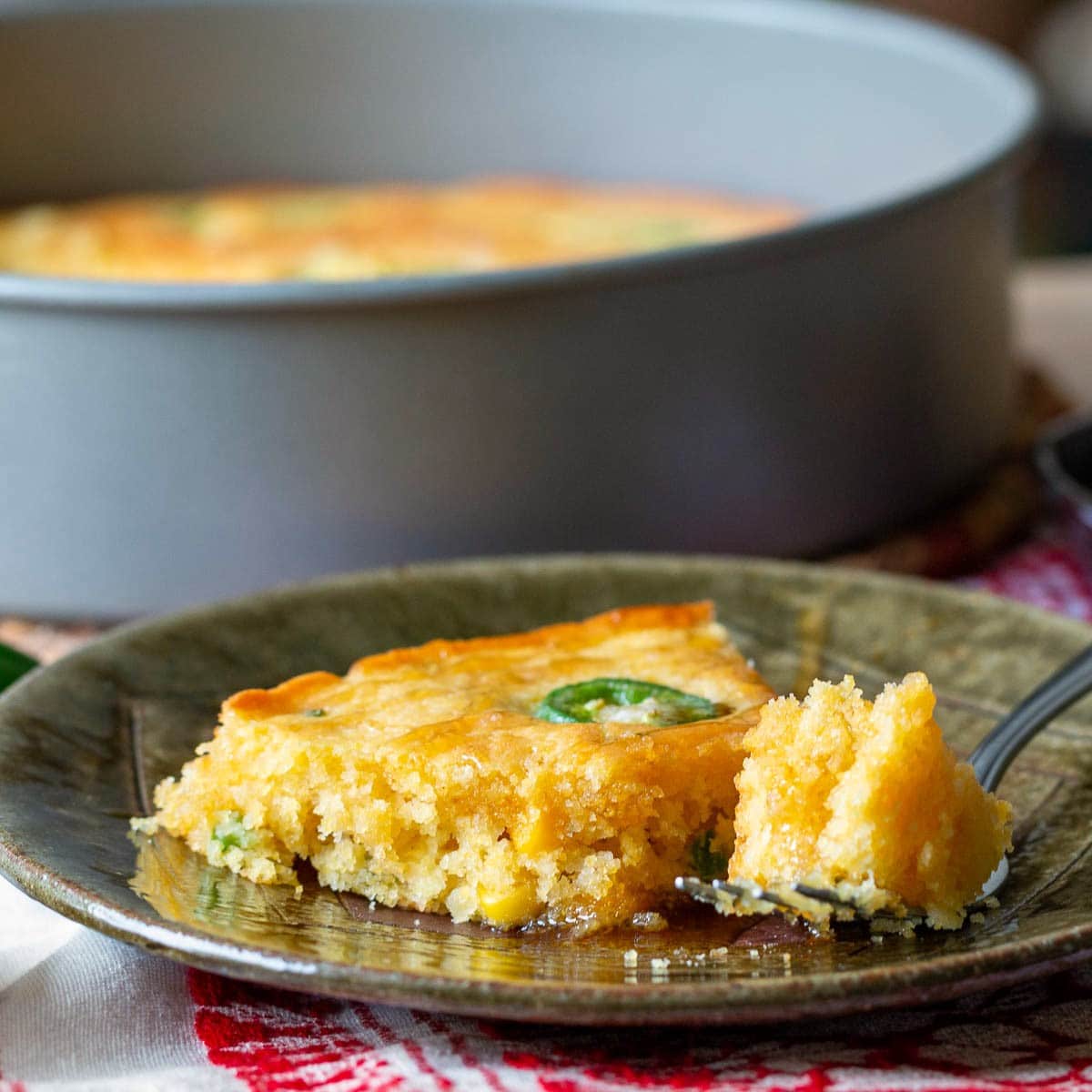Our ultimate air fryer Jiffy Cornbread served on a green plate with a fork.