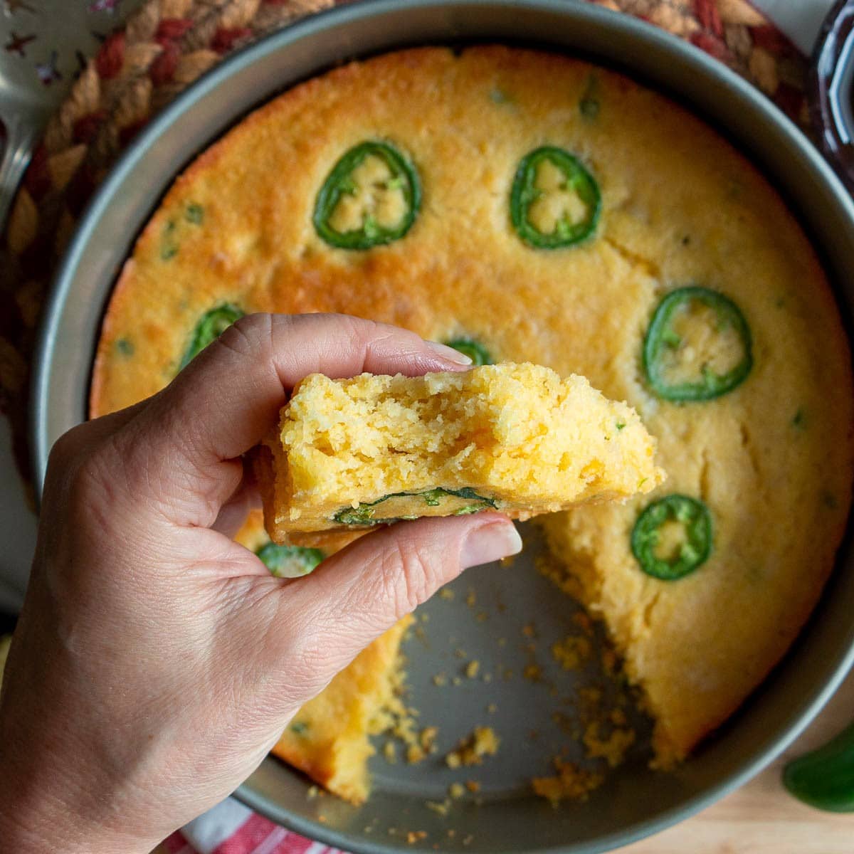 Holding a slice of cornbread in hands after taking a bite. 