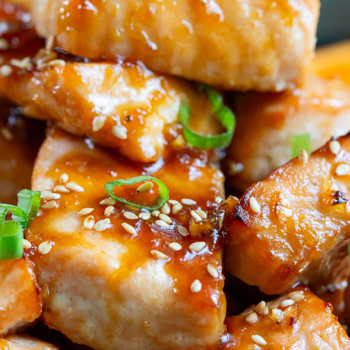 Closeup of the saucy air fryer salmon bites garnished with sesame seeds and green onion.