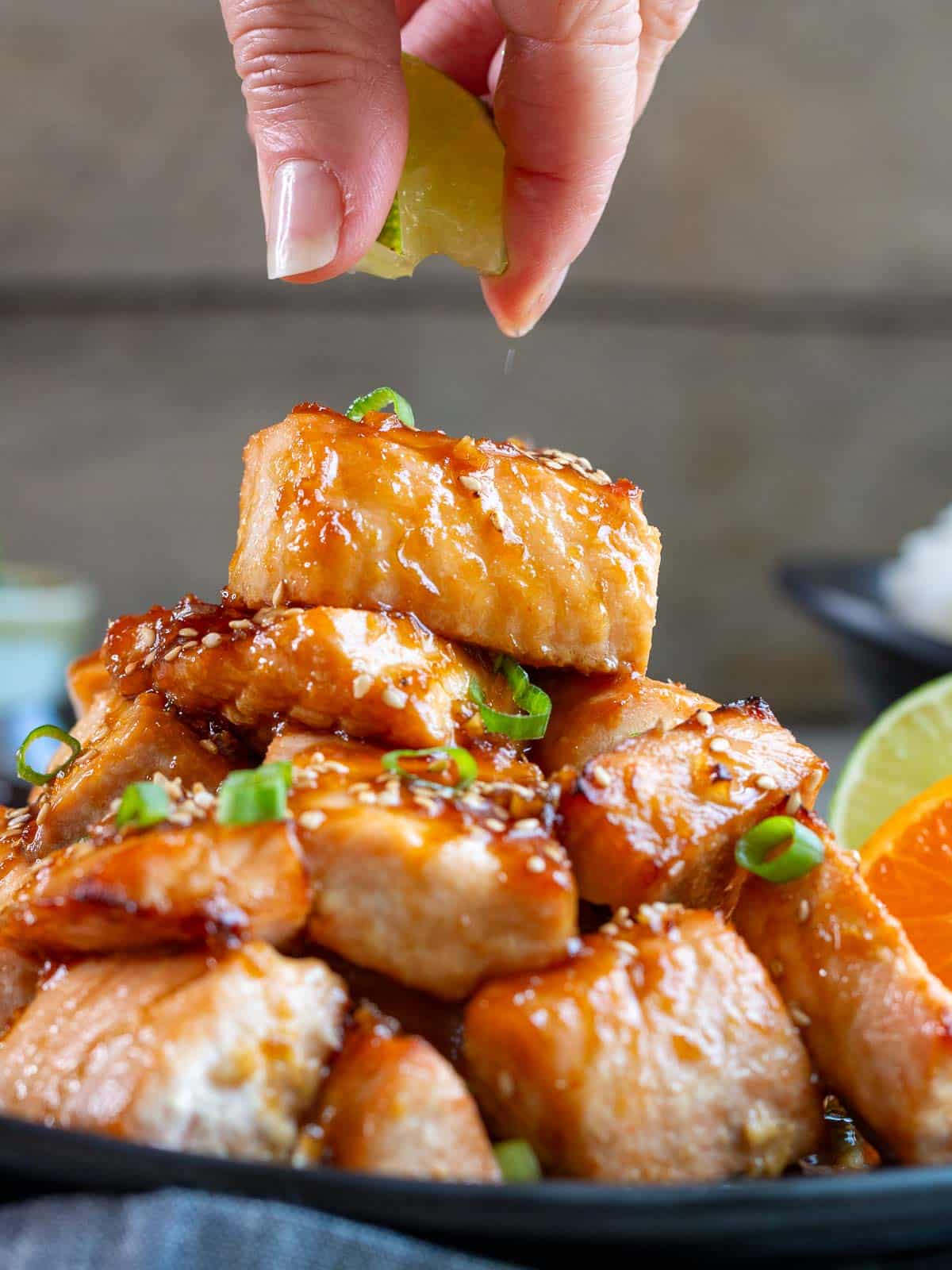 Orange glazed air fryer salmon bites getting a little squeeze of fresh lime juice on top. 