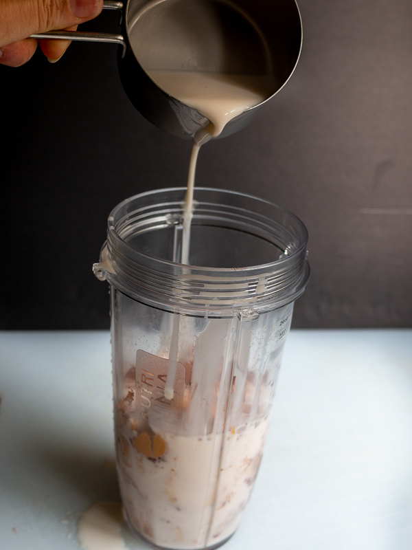 Pouring Silk brand unsweetened Almond and Coconut milk blend into blender with other ingredients. 