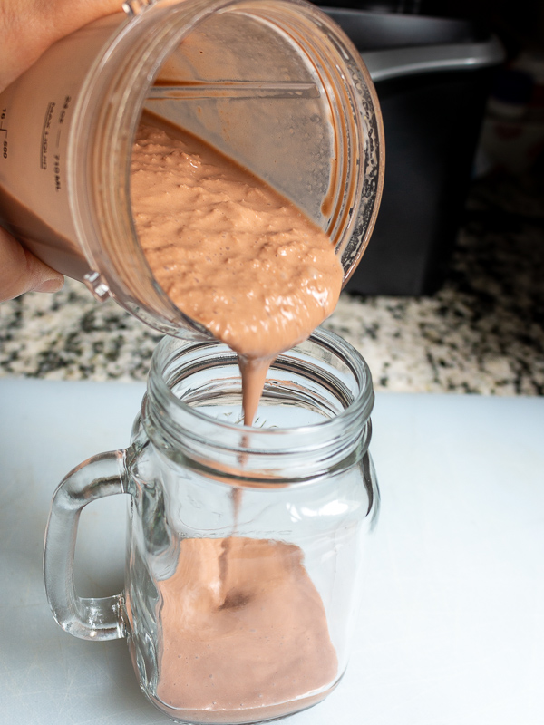 Pour rich thick chocolate peanut butter banana smoothie into a glass mug with a handle. 