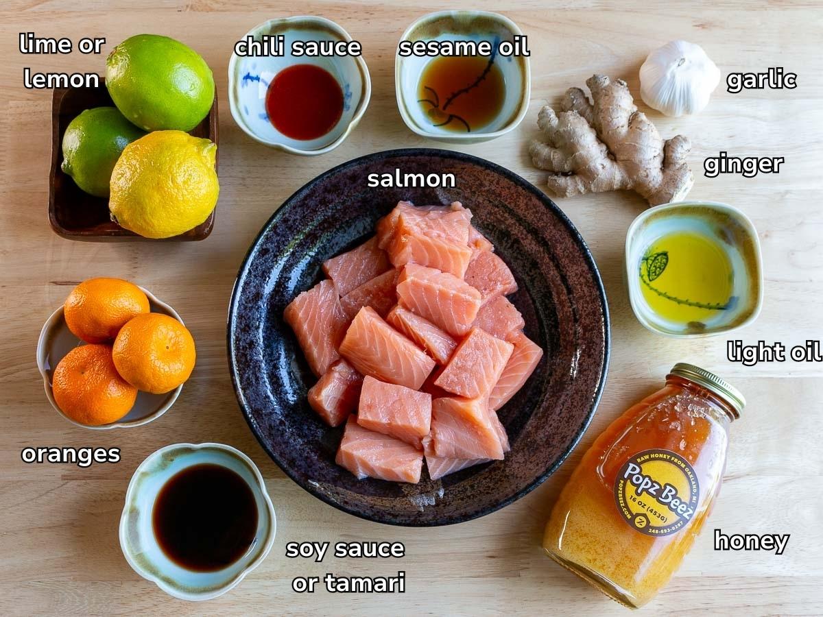 Ingredients to make salmon bites in the air fryer and a special orange salmon glaze laid out on a wooden table. 