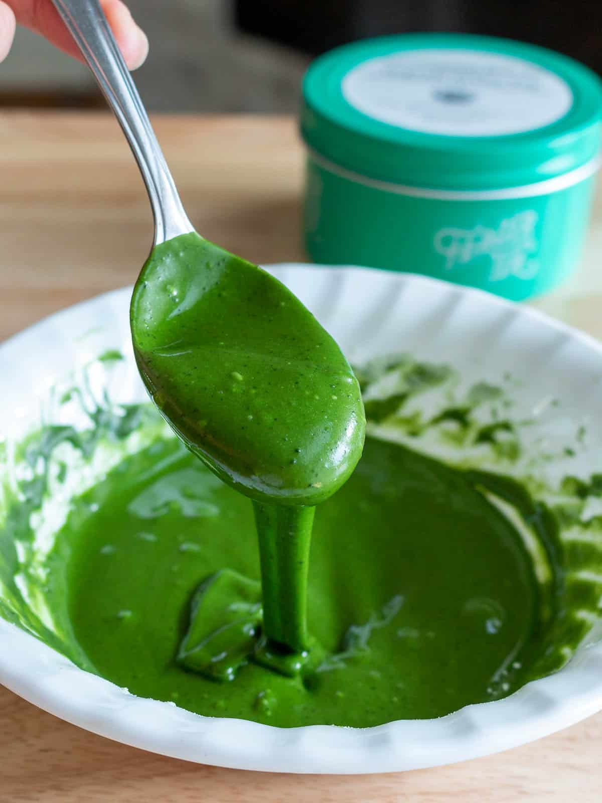 Matcha green tea glaze drizzling from a spoon into a white bowl.