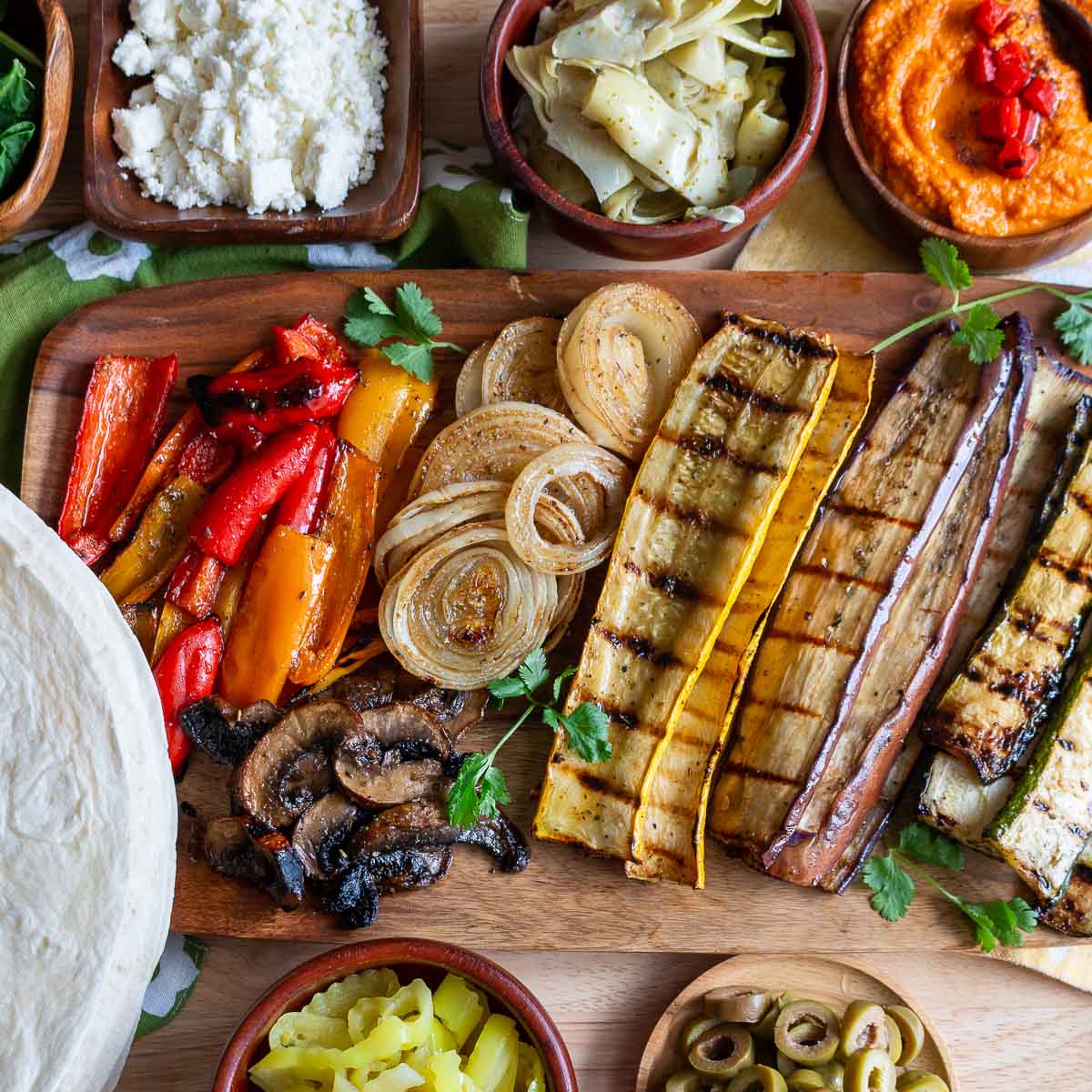 Grilled vegetables and all the toppings laid out on the table to assemble your own wrap.