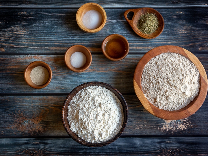 Ingredients laid out on a blue brown background with flour, yeast and all the toppings.