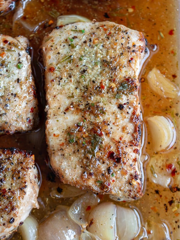 Close up top down photo of a cooked pork chop in the shallot wine sauce.